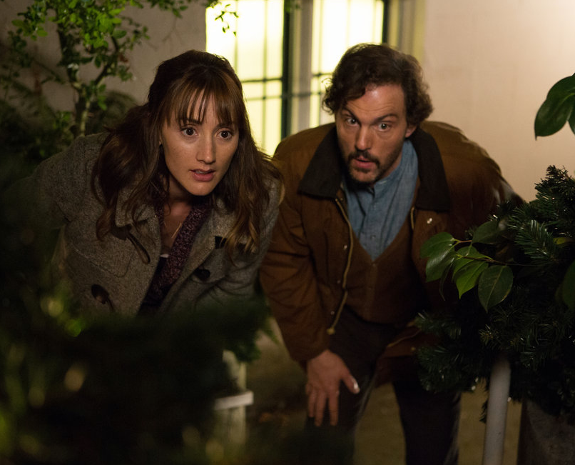 Rosalee and Monroe crouch behind bushes on Grimm.