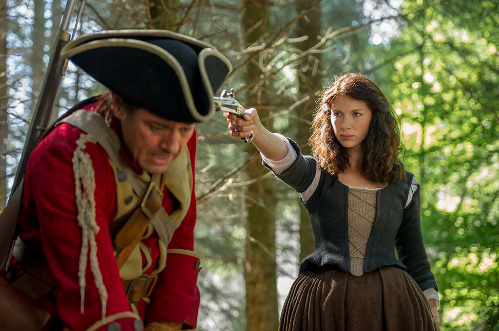 Claire holds a gun on a redcoat on Outlander