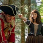 Claire holds a gun on a redcoat on Outlander